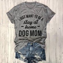Load image into Gallery viewer, A gray t-shirt with black text 'I JUST WANT TO BE A STAY AT HOME DOG MOM' printed on the front, paired with denim shorts with a frayed hem.